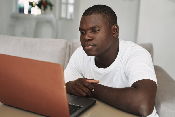 uomo aspetto africano a casa di fronte alla tecnologia per il tempo libero portatile - Foto, immagini
