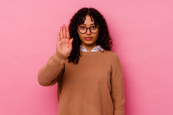Jonge gemengde ras vrouw geïsoleerd op roze achtergrond staan met uitgestrekte hand tonen stopteken, voorkomen dat u. - Foto, afbeelding