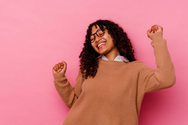Young mixed race woman isolated on pink background dancing and having fun. - Foto, imagen