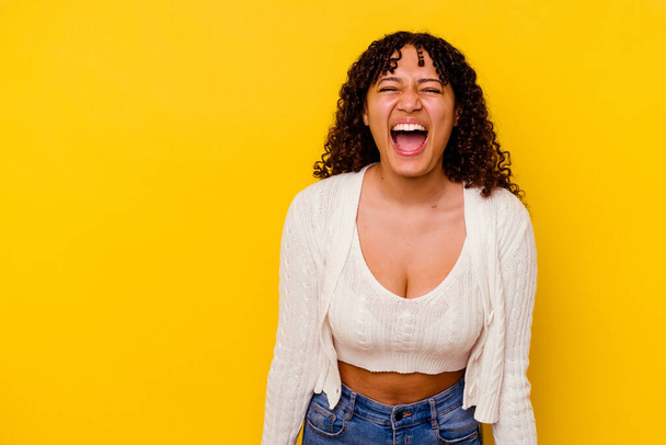 Young mixed race woman isolated on yellow background shouting very angry, rage concept, frustrated. - Foto, imagen