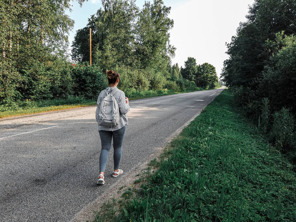 A woman with backpacks walking along the road. travel, camping, tourism and people concept. - Foto, imagen
