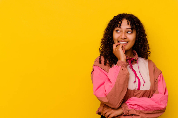 Young mixed race woman isolated on pink background relaxed thinking about something looking at a copy space. - Photo, Image
