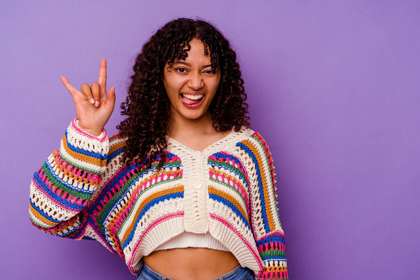 Young mixed race woman isolated on purple background showing a horns gesture as a revolution concept. - Fotoğraf, Görsel