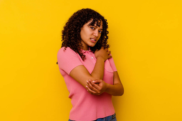 Young mixed race woman isolated on yellow background massaging elbow, suffering after a bad movement. - Foto, imagen