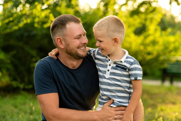 happy dad happily hugs his son in the garden. father's day. concept of family happiness, fatherhood, outdoor play together. - Fotoğraf, Görsel