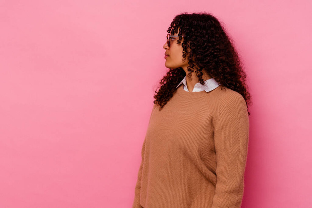 Young mixed race woman isolated on pink background gazing left, sideways pose. - Фото, изображение