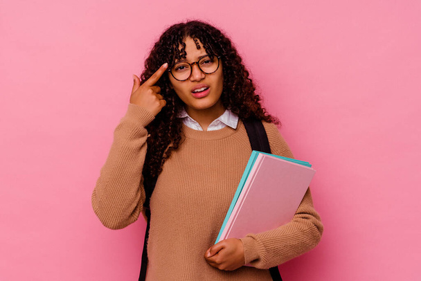 Jovem estudante mestiça mulher isolada sobre fundo rosa mostrando um gesto de decepção com indicador. - Foto, Imagem