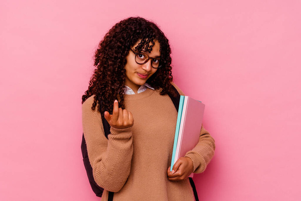 Mladý student smíšené rasy žena izolované na růžovém pozadí ukazuje prstem na vás, jako by pozvání přijít blíž. - Fotografie, Obrázek
