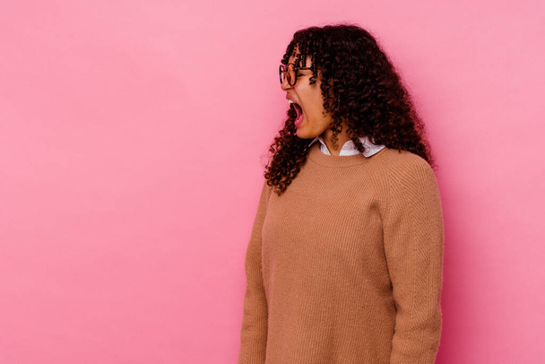 Junge Frau mit gemischter Rasse isoliert auf rosa Hintergrund schreit in Richtung Kopierraum - Foto, Bild