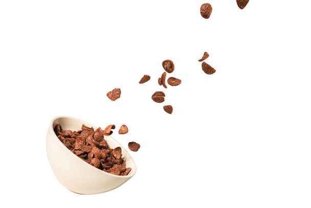 Chocolate corn flakes falling to the white bowl isolated on white. Motion. Copyspace. - Φωτογραφία, εικόνα