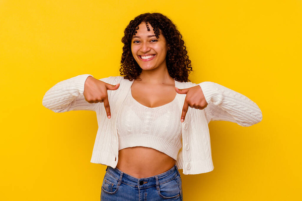 Young mixed race woman isolated on yellow background points down with fingers, positive feeling. - Fotoğraf, Görsel