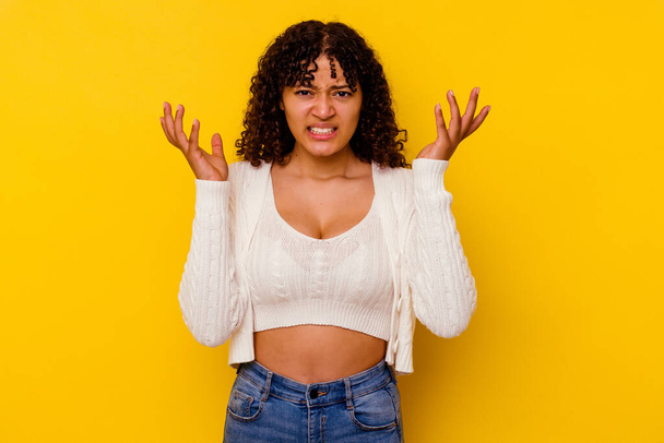 Young mixed race woman isolated on yellow background screaming with rage. - Fotografie, Obrázek