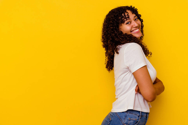 Młoda mieszana rasa kobieta odizolowana na żółtym tle uśmiechnięta pewna siebie ze skrzyżowanymi ramionami. - Zdjęcie, obraz