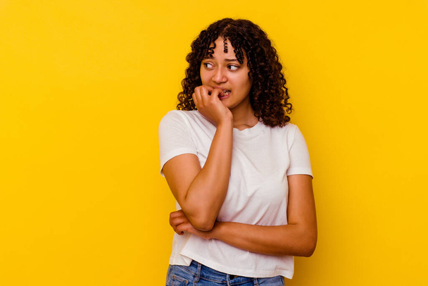 Young mixed race woman isolated on yellow background biting fingernails, nervous and very anxious. - Foto, Imagen