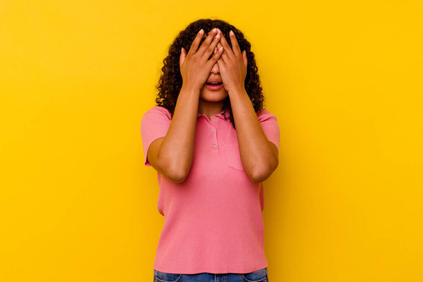 Young mixed race woman isolated on yellow background afraid covering eyes with hands. - Zdjęcie, obraz