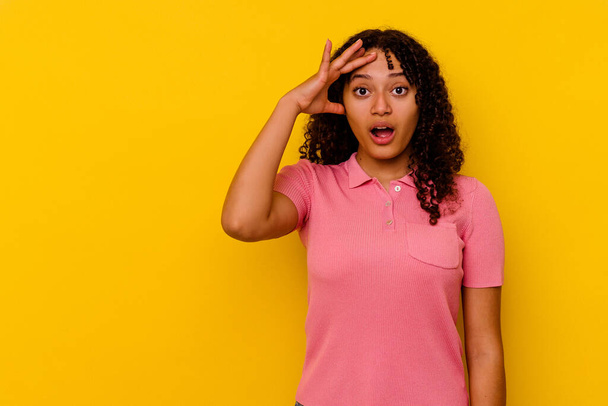 Young mixed race woman isolated on yellow background looking far away keeping hand on forehead. - Photo, image