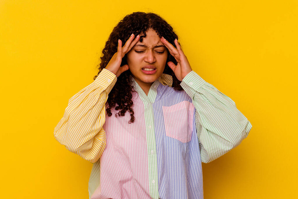 Молодая женщина смешанной расы изолирована на желтом фоне с головной болью, касаясь лица. - Фото, изображение