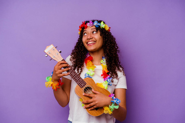 jonge hawaiiaanse vrouw spelen ukelele geïsoleerd op paarse achtergrond - Foto, afbeelding
