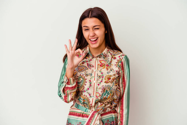 Jeune femme indienne isolée sur fond blanc clin d'oeil et tient un geste correct avec la main. - Photo, image