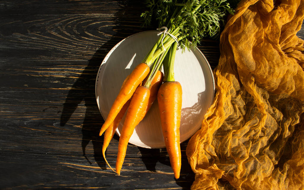 fresh whole carrots on wooden background - 写真・画像