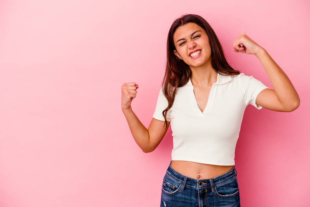 Young Indian woman isolated on pink background raising fist after a victory, winner concept. - 写真・画像