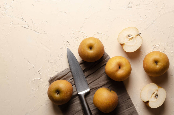 Asian pears with a silver knife and a brown piece of cloth, on a light background. - Photo, Image