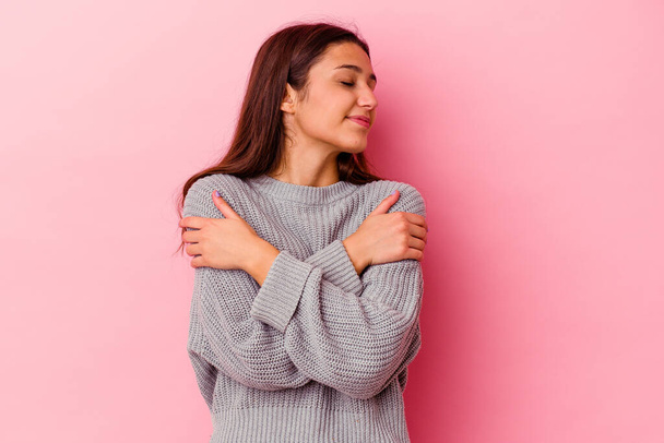 Young Indian woman isolated on pink background hugs, smiling carefree and happy. - Zdjęcie, obraz