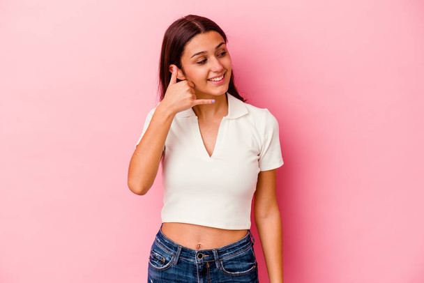 Young Indian woman isolated on pink background showing a mobile phone call gesture with fingers. - Photo, Image