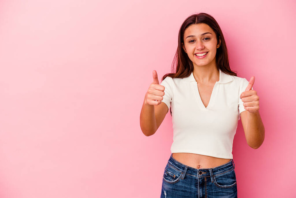 Young Indian woman isolated on pink background smiling and raising thumb up - 写真・画像