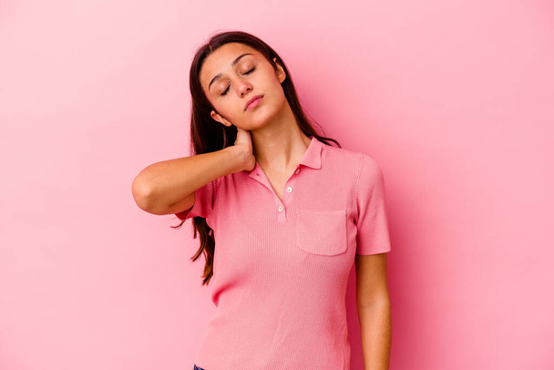 Young Indian woman isolated on pink background having a neck pain due to stress, massaging and touching it with hand. - Photo, Image