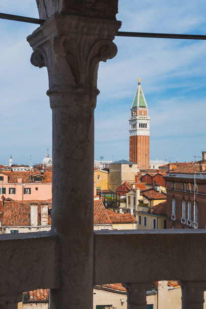 Näkymä San Marco kellotorni yli perinteisten venetsialaisten talojen katsottuna sarakkeiden välillä Venetsiassa, Italiassa - Valokuva, kuva