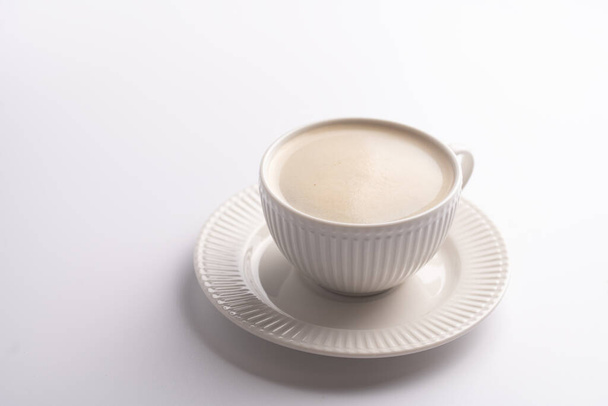 A white porcelain cup with coffee drink cappuccino on a white saucer plate on a white surface - Foto, Imagem