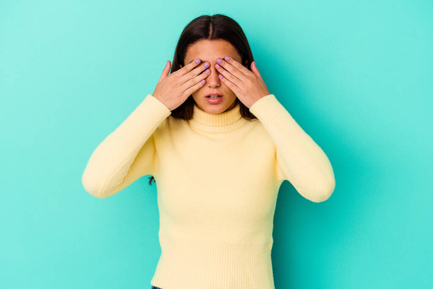 Young Indian woman isolated on blue background afraid covering eyes with hands. - Photo, Image