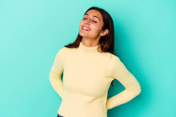 Young Indian woman isolated on blue background relaxed and happy laughing, neck stretched showing teeth. - Photo, Image