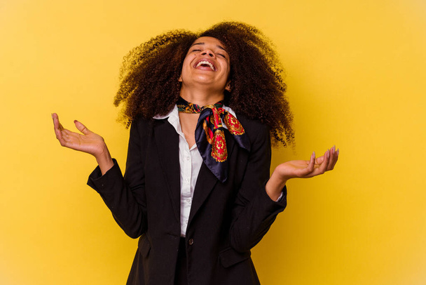 Die junge afroamerikanische Stewardess auf gelbem Hintergrund lacht fröhlich viel. Glückskonzept. - Foto, Bild