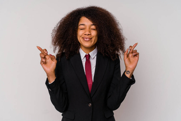 Νεαρή Αφρο-Αμερικανίδα επιχειρηματίας φορώντας κοστούμι απομονωμένο σε λευκό φόντο σταυρώνει τα δάχτυλα για την τύχη - Φωτογραφία, εικόνα