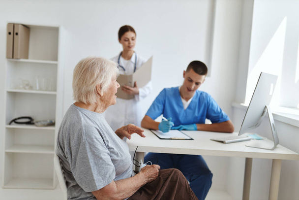 starší žena sedící na návštěvě lékaře s diagnostikou léčby zdravotní sestry - Fotografie, Obrázek