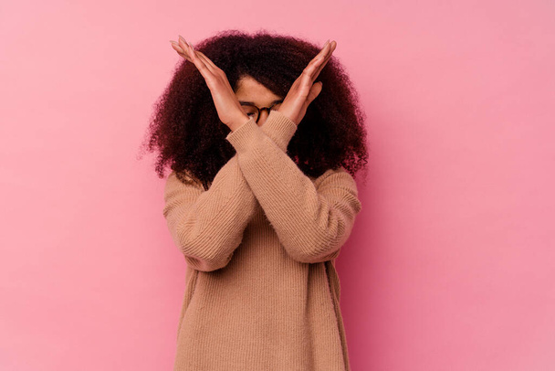 Giovane donna afroamericana isolata su sfondo rosa tenendo due braccia incrociate, concetto di negazione. - Foto, immagini