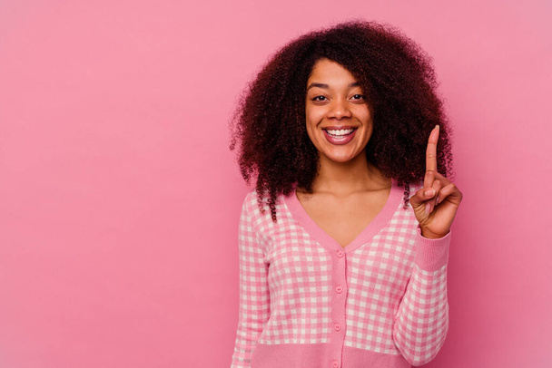 Nuori afrikkalainen amerikkalainen nainen eristetty vaaleanpunainen tausta osoittaa numero yksi sormella. - Valokuva, kuva