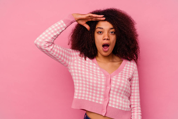 Jonge Afro-Amerikaanse vrouw geïsoleerd op roze achtergrond schreeuwt luid, houdt ogen geopend en handen gespannen. - Foto, afbeelding