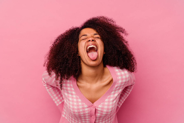 Junge afrikanisch-amerikanische Frau isoliert auf rosa Hintergrund lustig und freundlich herausstreckende Zunge. - Foto, Bild