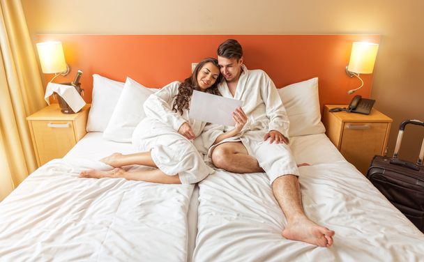Nuori pariskunta makaa hotellihuoneen sängyssä
 - Valokuva, kuva