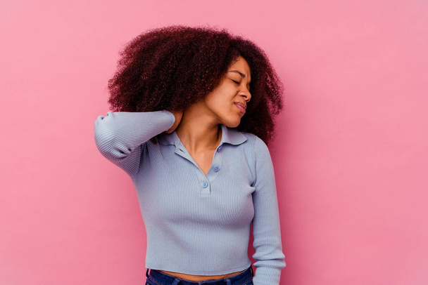 Młoda Afroamerykanka wyizolowana na różowym tle z bólem szyi spowodowanym stresem, masażem i dotykaniem jej dłonią. - Zdjęcie, obraz