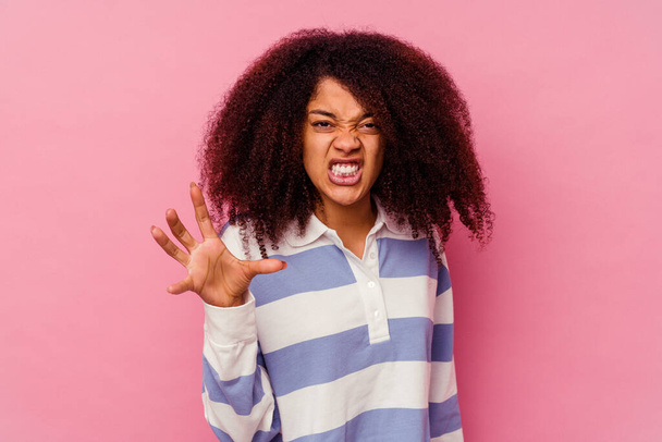 Young african american woman isolated on pink background showing claws imitating a cat, aggressive gesture. - Foto, afbeelding
