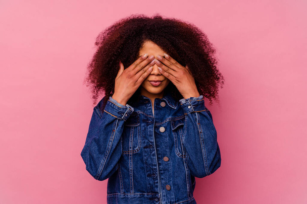 Young african american woman isolated on pink background afraid covering eyes with hands. - Фото, изображение