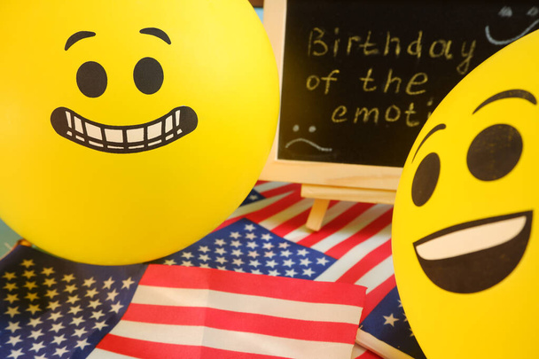 Κίτρινα μπαλόνια emoji στο φόντο του πίνακα με την επιγραφή εκδήλωση και αμερικανικές σημαίες. - Φωτογραφία, εικόνα