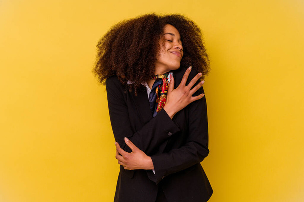 Giovane hostess aerea afroamericana isolato su sfondo giallo abbracci, sorridente spensierato e felice. - Foto, immagini