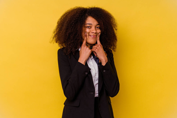 Giovane hostess aerea afroamericana isolato su sfondo giallo dubitare tra due opzioni. - Foto, immagini