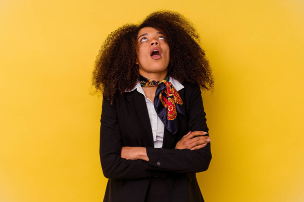 Young African American air hostess isolated on yellow background tired of a repetitive task. - Photo, Image