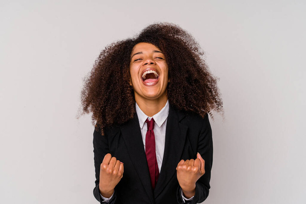 Νεαρή Αφρο-Αμερικανίδα επιχειρηματίας που φοράει κοστούμι απομονωμένη σε λευκό φόντο ζητωκραυγάζοντας ανέμελη και ενθουσιασμένη. Έννοια νίκης. - Φωτογραφία, εικόνα